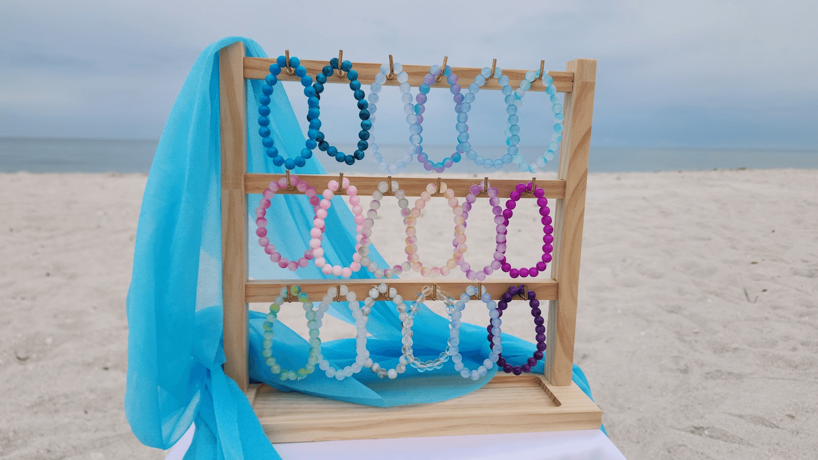 A rack of colorful beaded bracelets displayed on the beach