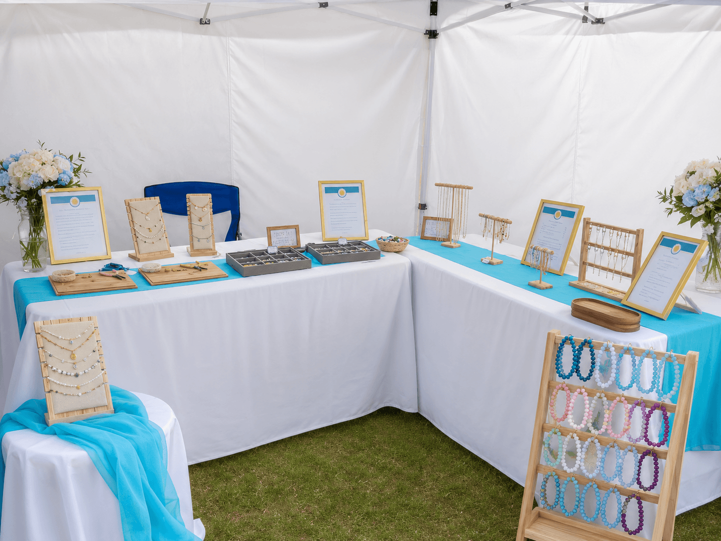 A styled tent display with jewelry stands and fresh florals for a pop-up market